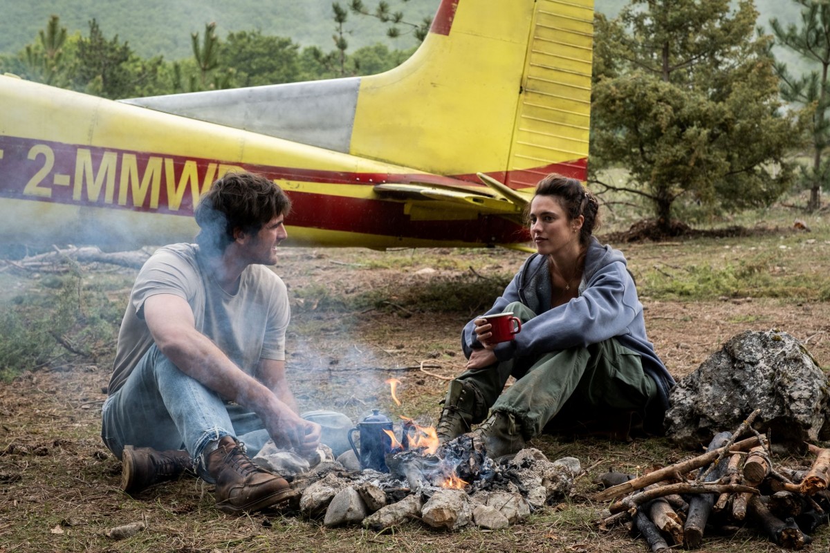 Jacob Elordi ja Margaret Qualley keskustelevat nuotion ääressä elokuvassa The Dog Stars (© 20th Century Studios)