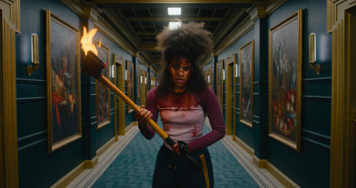 Zazie Beetz seisoo kirves kädessä käytävällä elokuvassa They Will Kill You (© Warner Bros. Pictures)