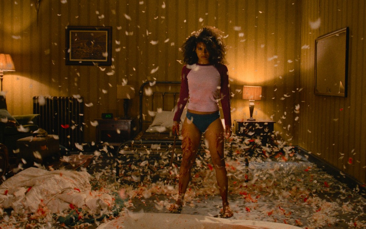Zazie Beetz seisoo alushousuisillaan huoneen ja höyhenten keskellä elokuvassa They Will Kill You (© Warner Bros. Pictures)