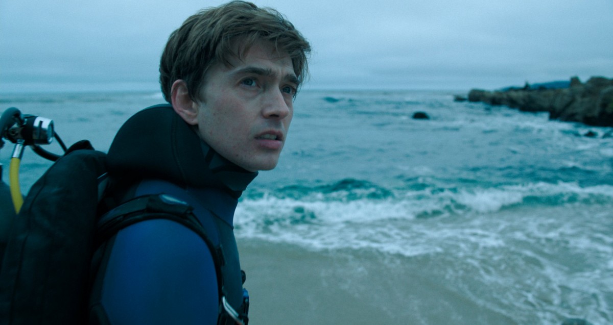 Austin Abrams seisoo rannalla elokuvassa Whalefall (© Disney)