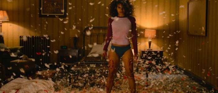 Zazie Beetz seisoo alushousuisillaan huoneen ja höyhenten keskellä elokuvassa They Will Kill You (© Warner Bros. Pictures)